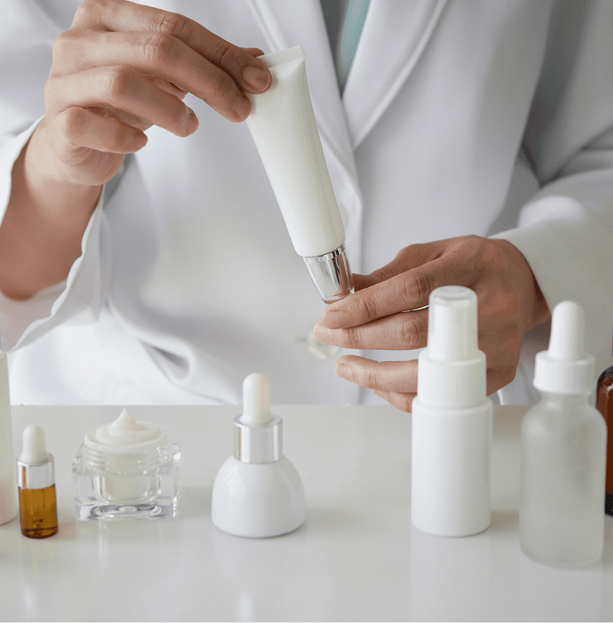 Hands holding a cream tube and bottles